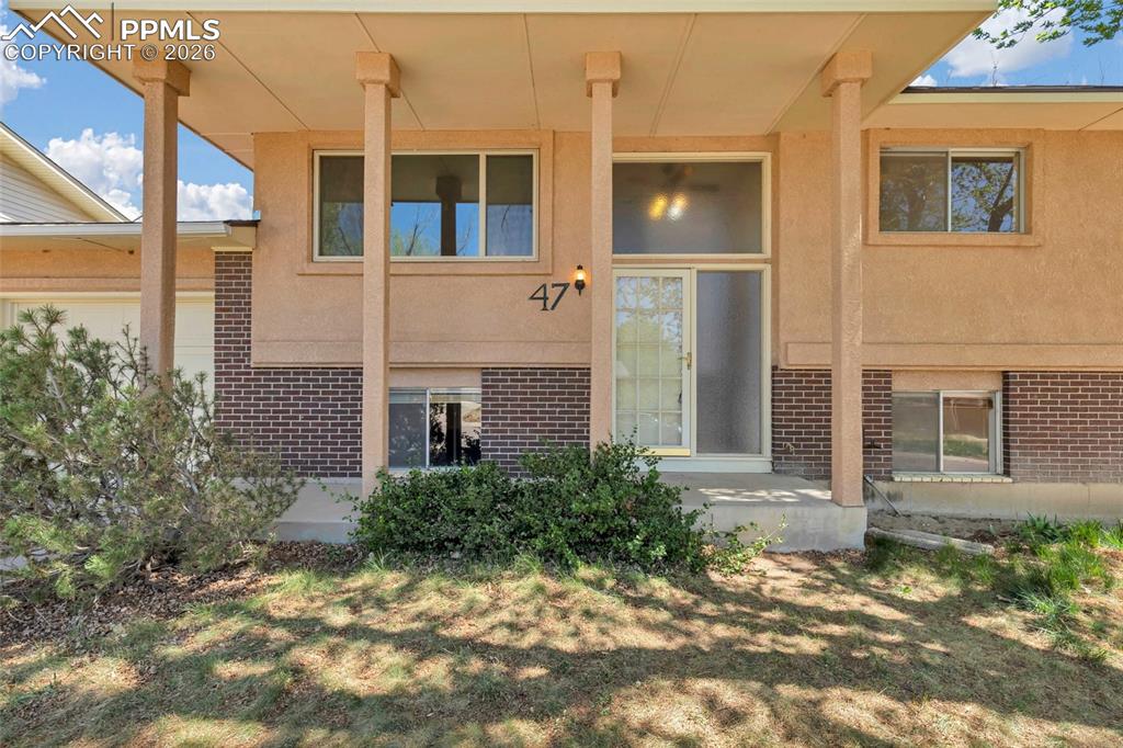 Image 4 of 36: Stucco and brick exterior featuring a covered entryway with structural colu
