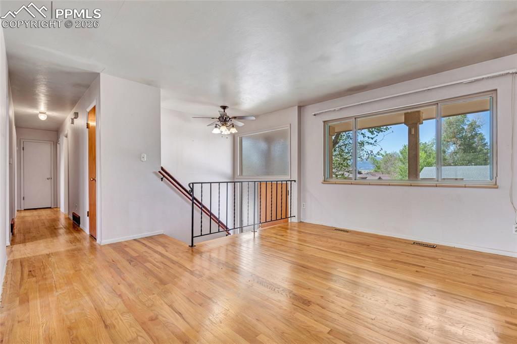 Image 6 of 36: Hardwood flooring throughout a spacious room featuring a large horizontal w