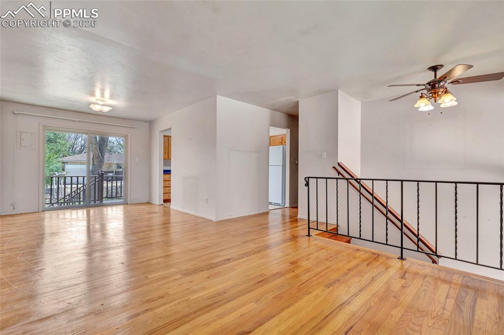 Image 7 of 36: Spacious room featuring wood-finish flooring, white walls, and a sliding gl
