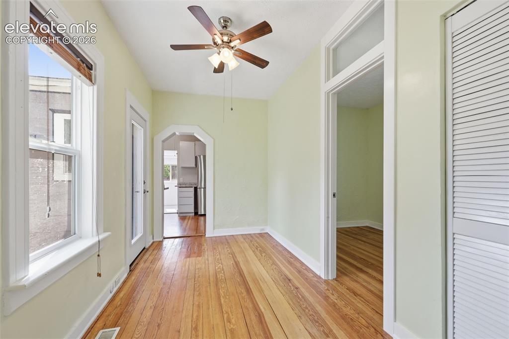 Image 11 of 40: Dining area with pine hardwood flooring, arched opening, a ceiling fan, woo