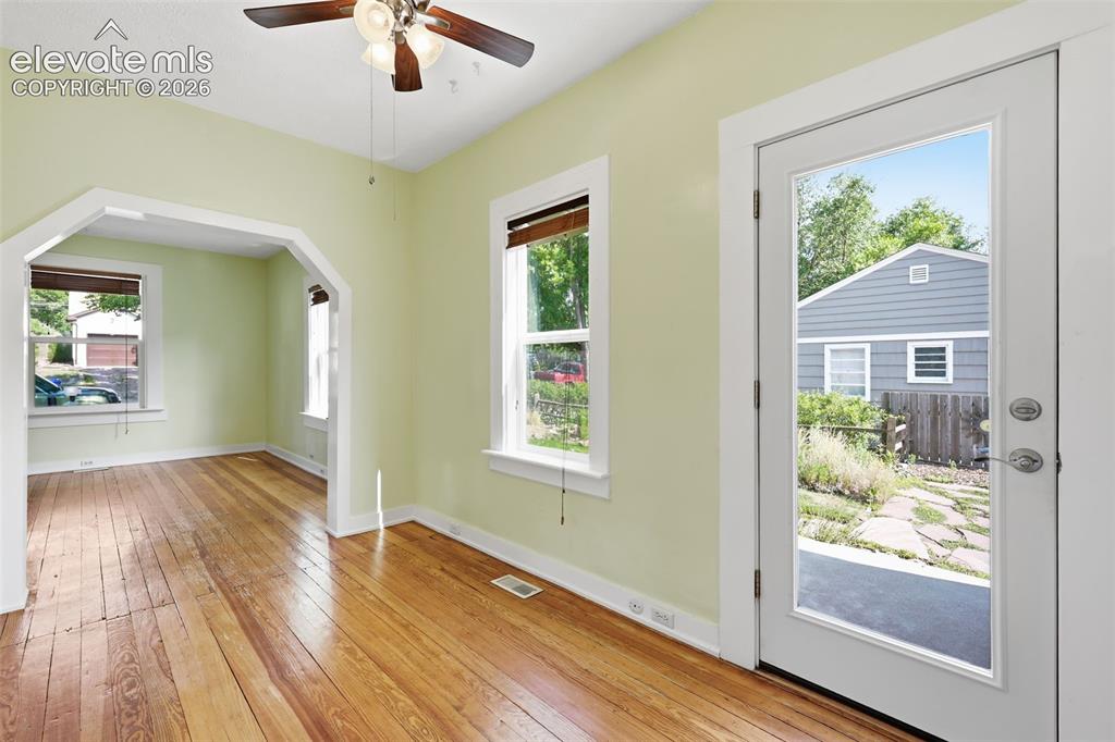 Image 12 of 40: Dining area with pine hardwood flooring, arched opening, a ceiling fan, woo