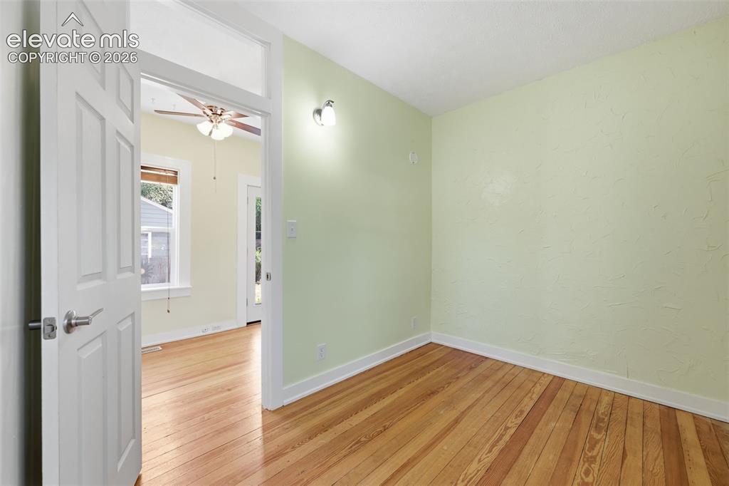 Image 14 of 40: Main-floor bedroom with pine hardwood flooring throughout, white trim, and 