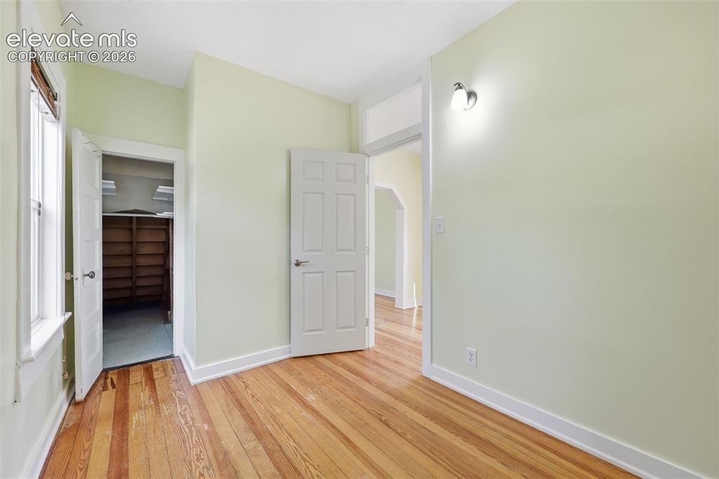 Image 15 of 40: Main-floor bedroom with pine hardwood flooring throughout, walk-in closet,