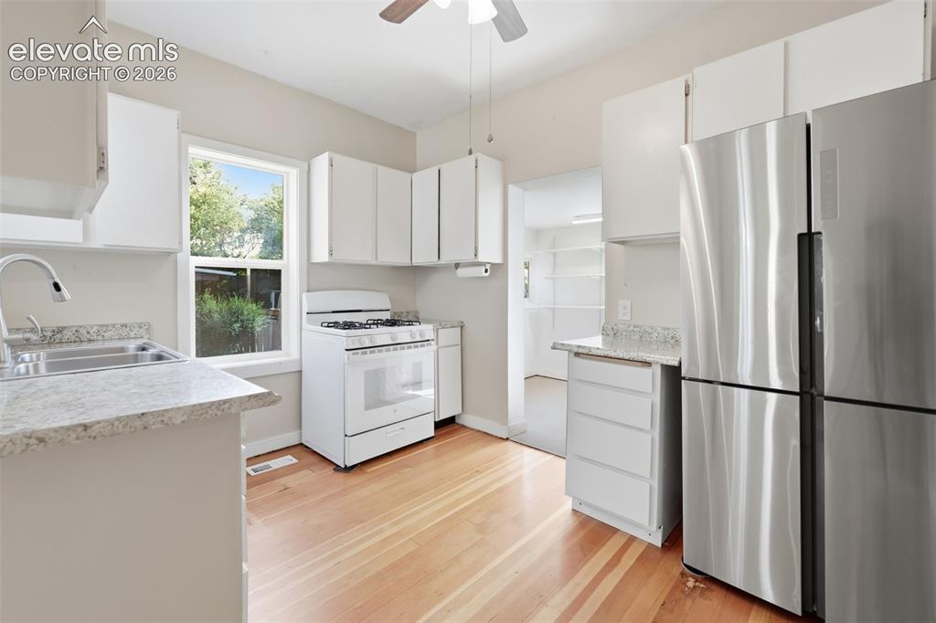 Image 16 of 40: Kitchen featuring pine hardwood flooring, stainless steel refrigerator, whi