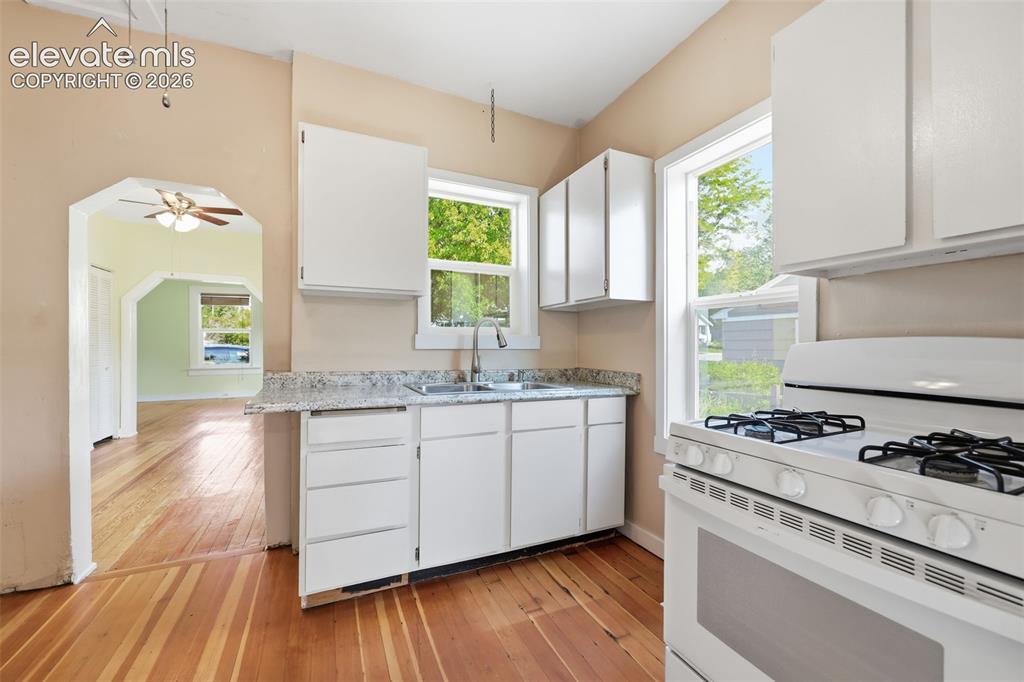 Image 17 of 40: Kitchen featuring white cabinetry, a double basin sink, light-toned counter