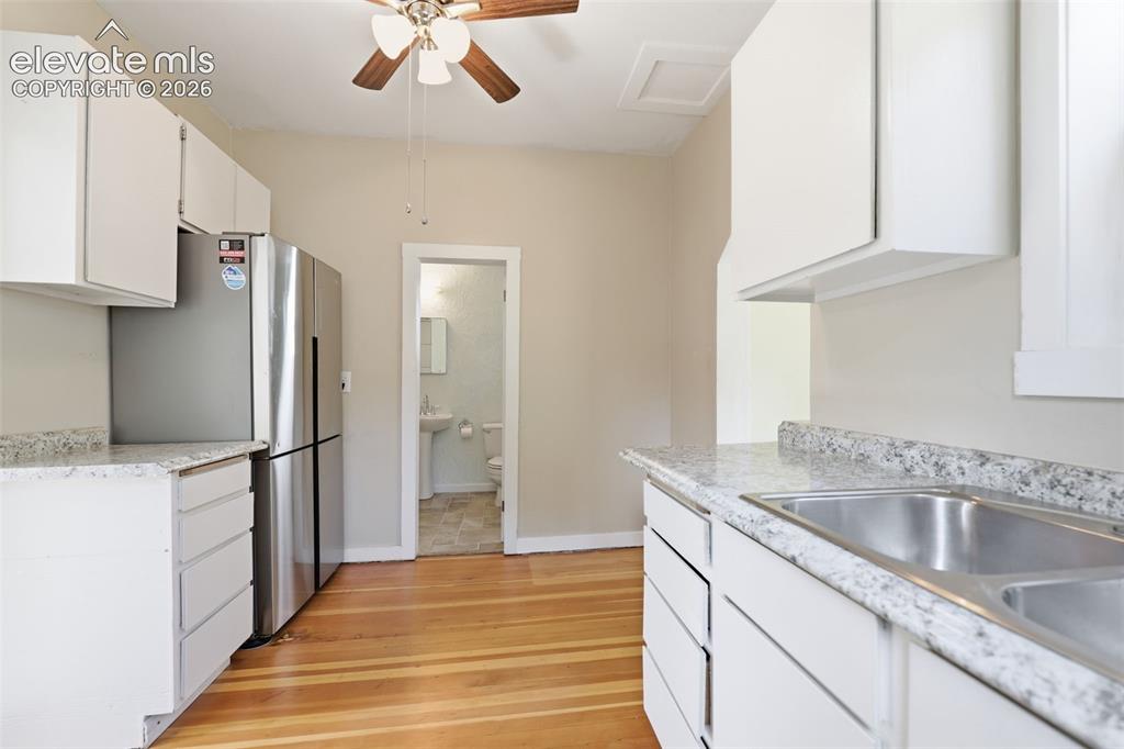 Image 18 of 40: Kitchen featuring white cabinetry, a double basin sink, light-toned counter