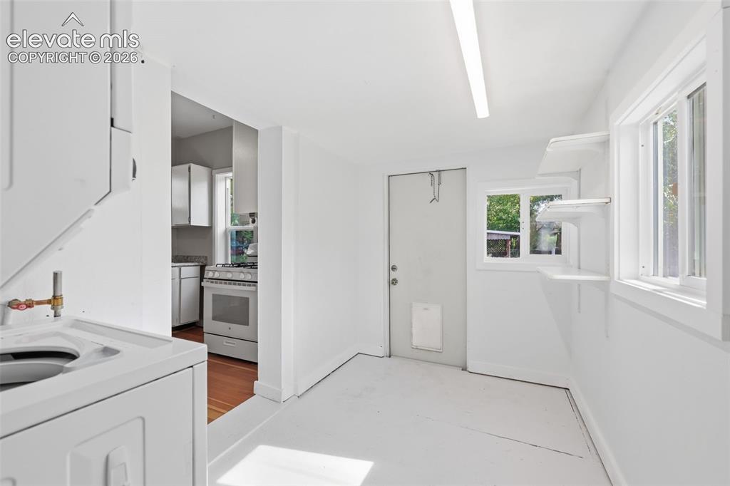 Image 19 of 40: Laundry room featuring an integrated washer and dryer unit, built-in shelvi