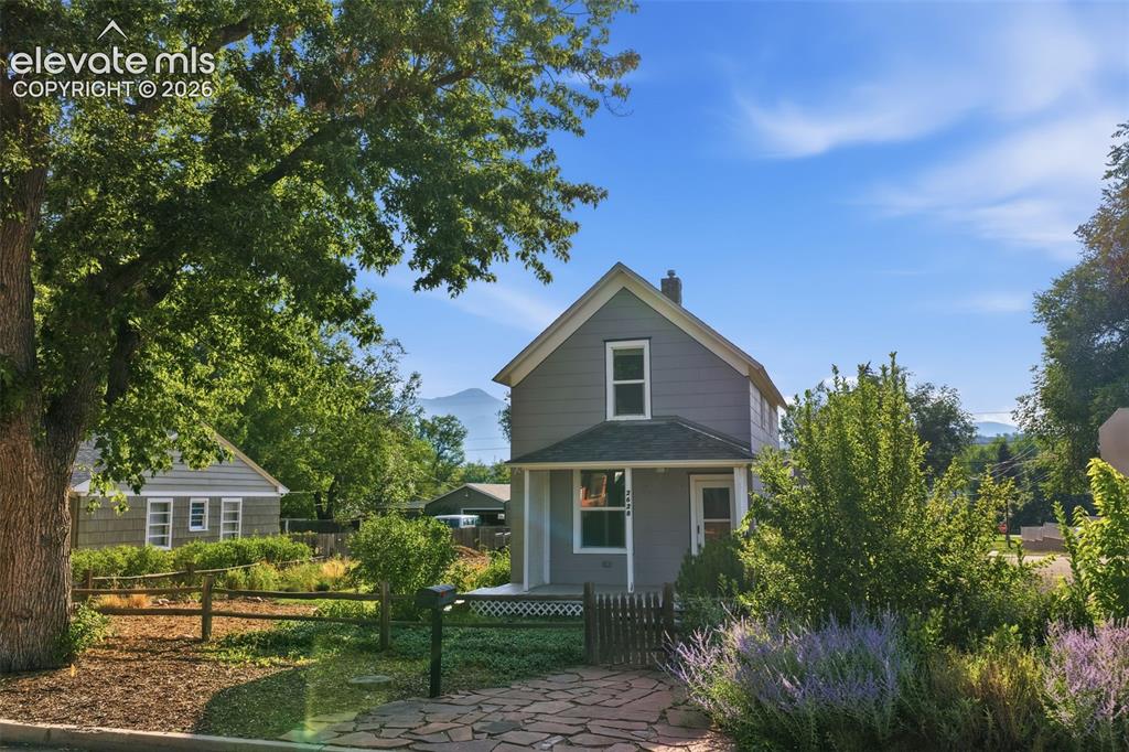 Image 2 of 40: Gabled roofline with a chimney, gray siding exterior, covered front porch, 