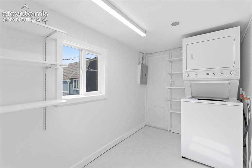 Image 20 of 40: Laundry room featuring an integrated washer and dryer unit, built-in shelvi