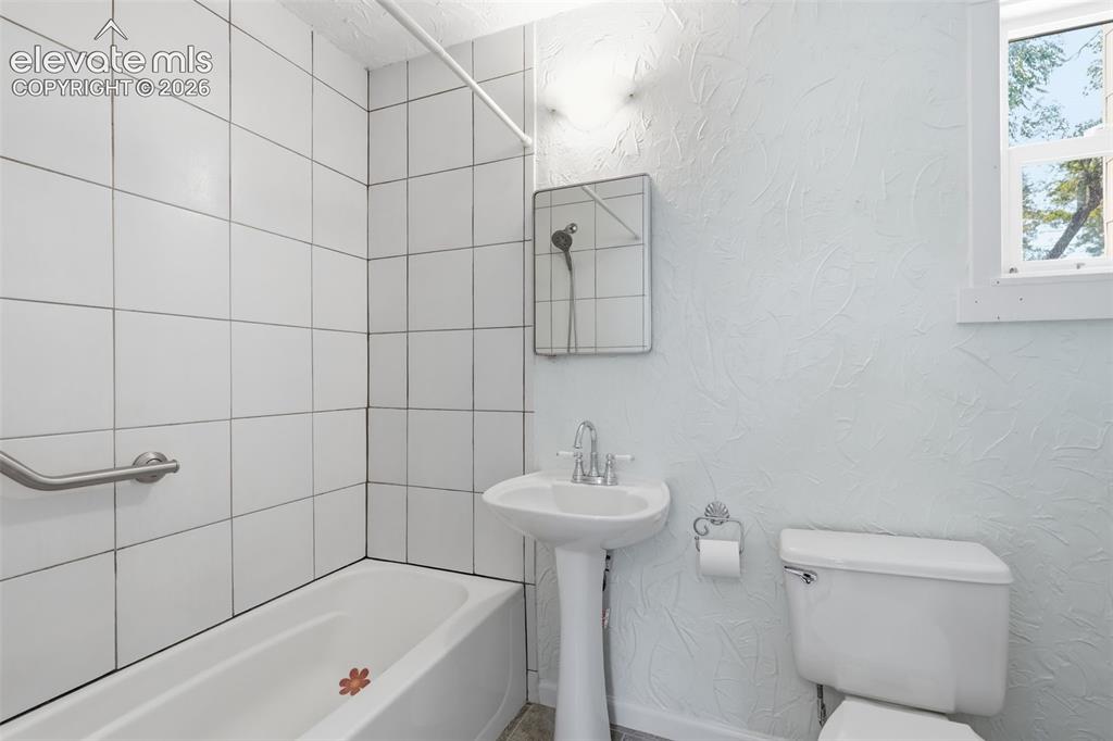 Image 21 of 40: Main-floor bathroom featuring a pedestal sink, white toilet, and tub with w