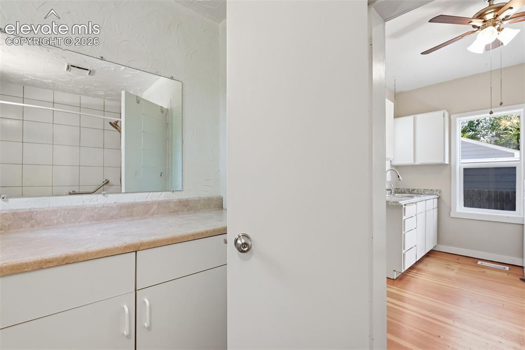 Image 22 of 40: Bathroom vanity with white cabinetry, a built-in mirror, and light-toned co