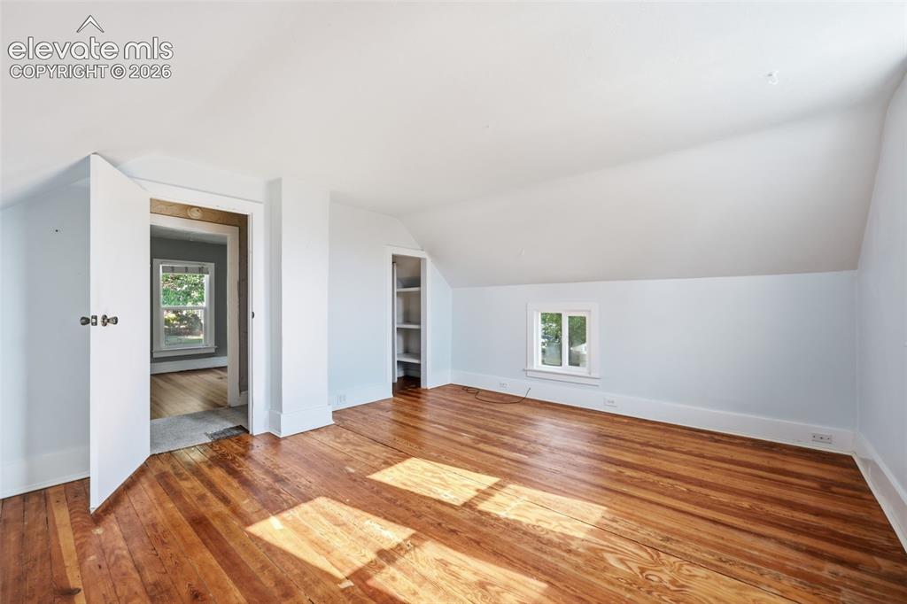 Image 25 of 40: Primary bedroom with pine hardwood flooring, painted walls, sloped ceilings