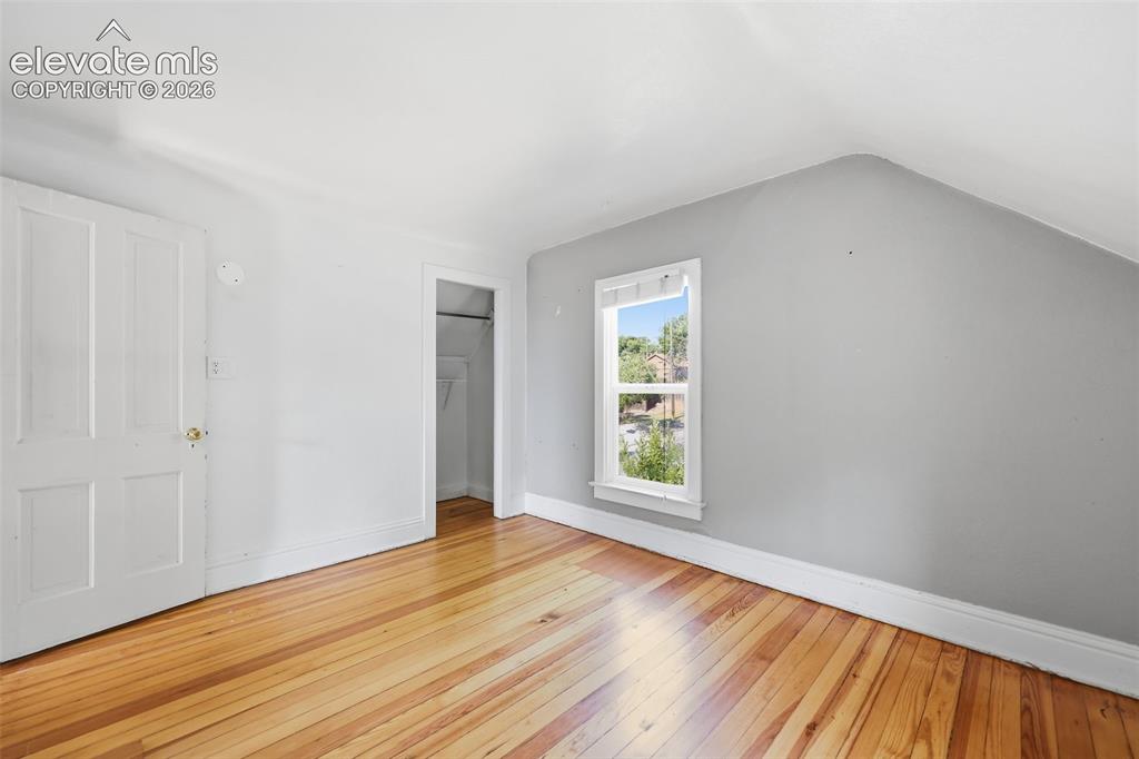 Image 27 of 40: Secondary upper bedroom with pine hardwood flooring, white paneled door, sl