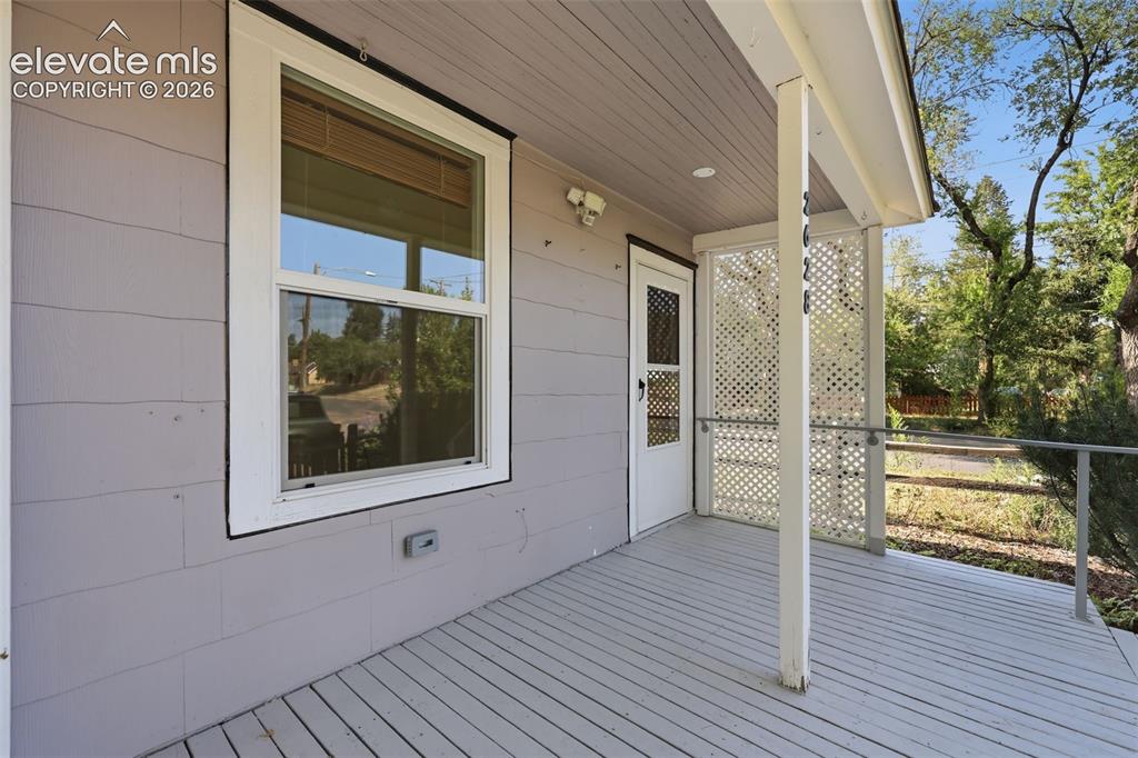 Image 3 of 40: Front porch with wood decking, white lattice privacy screen, and white rail