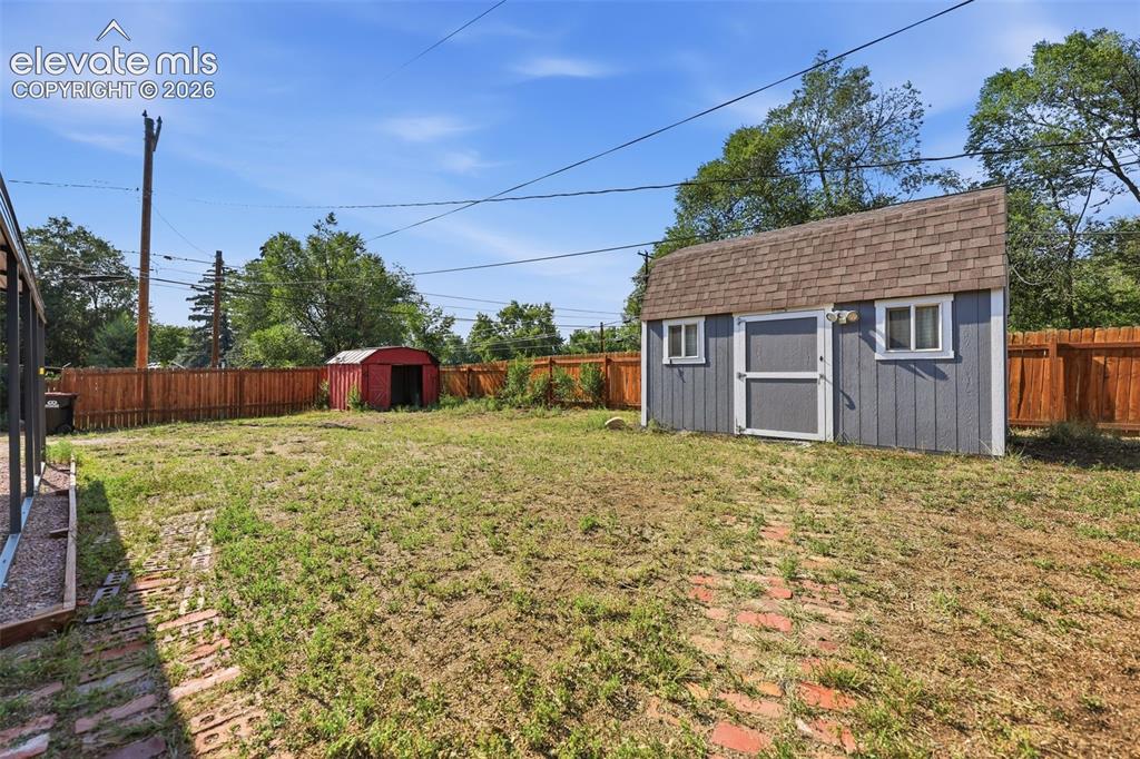 Image 32 of 40: Spacious backyard featuring a utility shed with a shingle roof and two wind