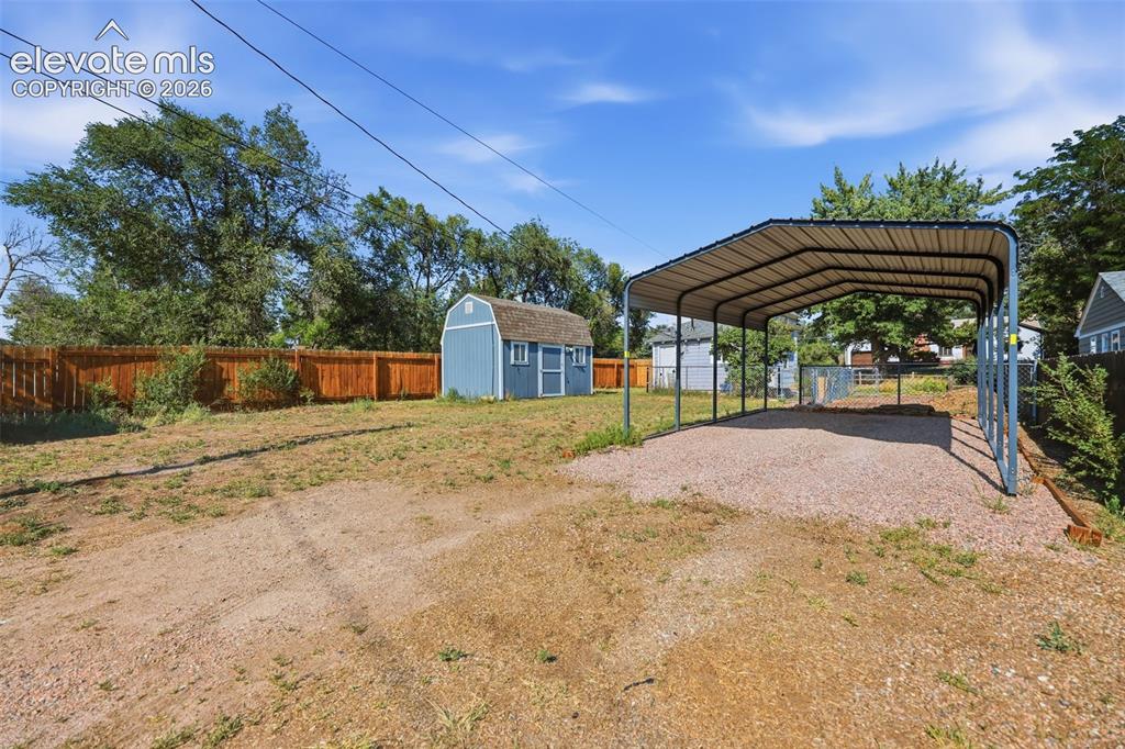 Image 33 of 40: Spacious backyard featuring a utility shed with a shingle roof and two wind