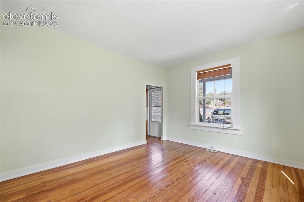 Image 9 of 40: Living room with pine hardwood flooring, painted walls, window with wooden 