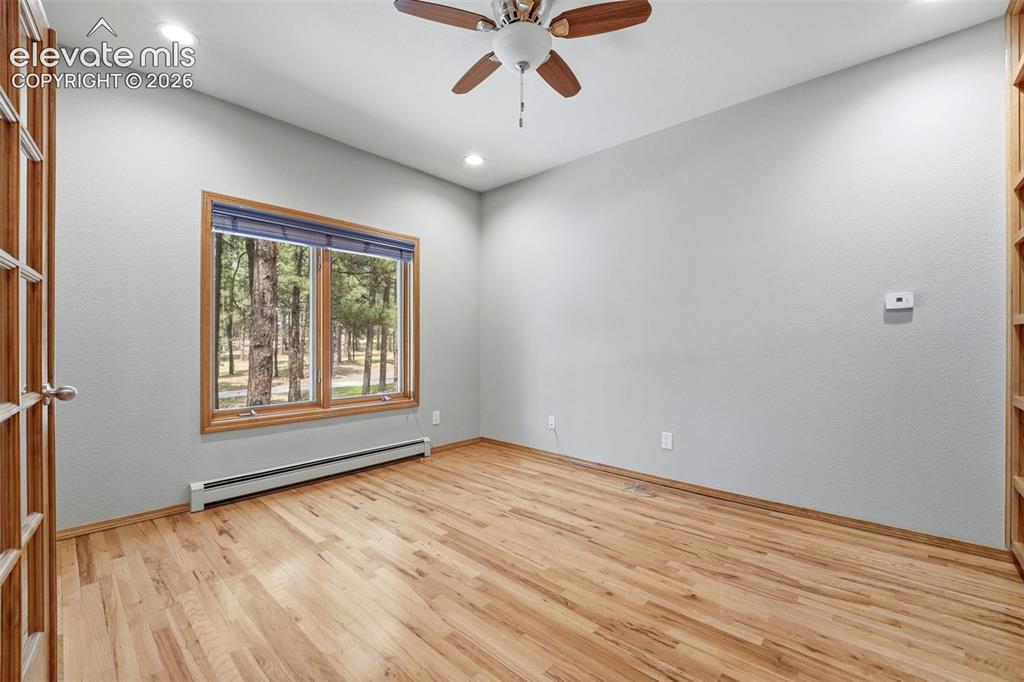 Image 11 of 40: Room featuring wood-finish flooring, a wood-framed window with a tree-lined