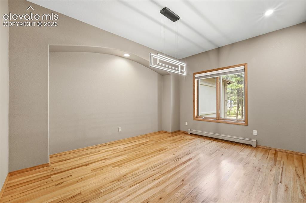 Image 14 of 40: Spacious room featuring wood-finish flooring, a modern linear chandelier, a