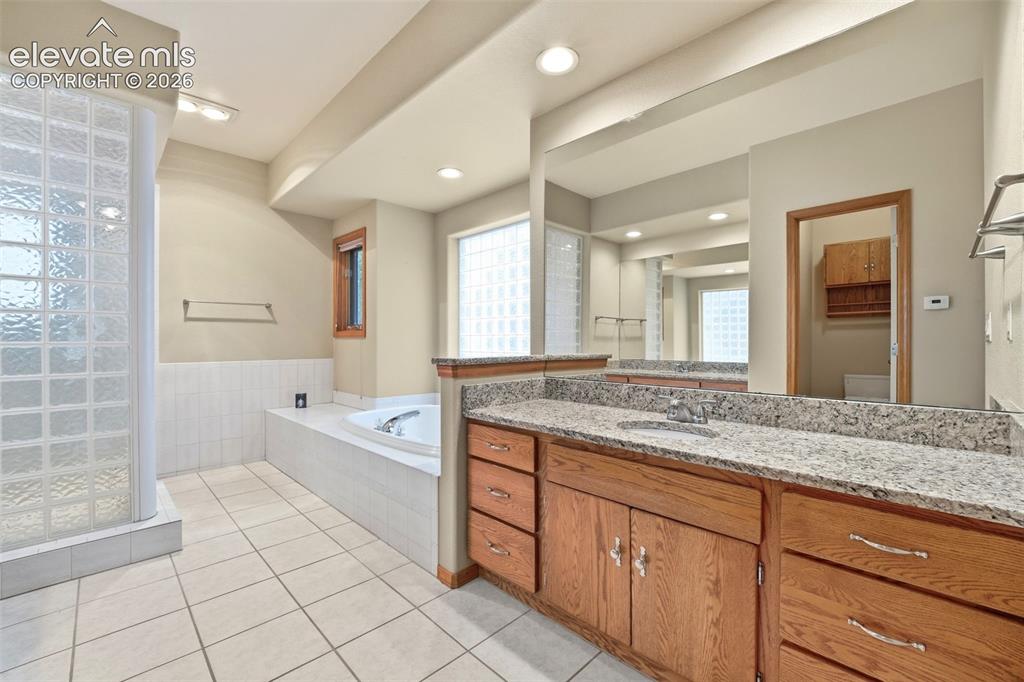 Image 16 of 40: Bathroom featuring a large vanity with a granite countertop, dual sinks, an