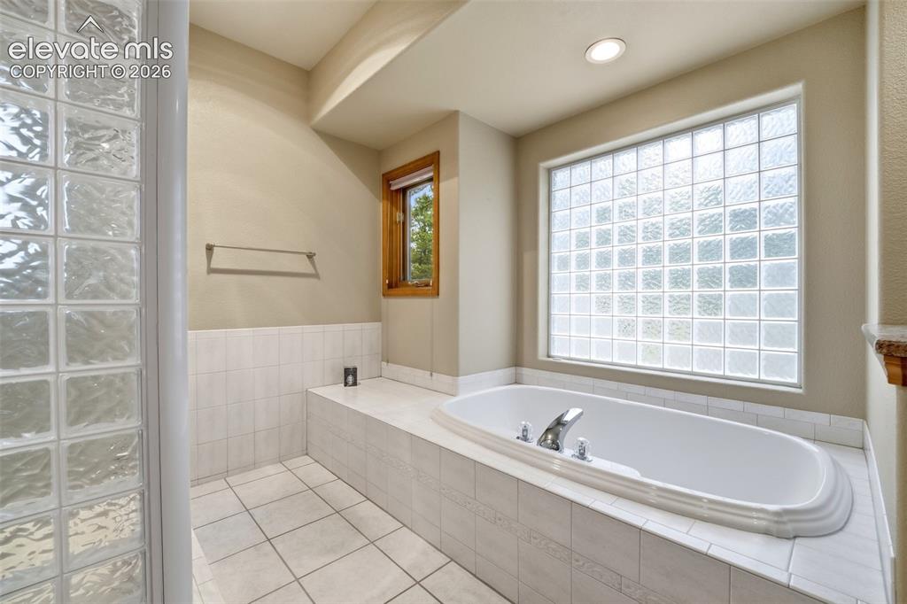 Image 17 of 40: Bathroom featuring a built-in soaking tub with chrome fixtures, a large gla