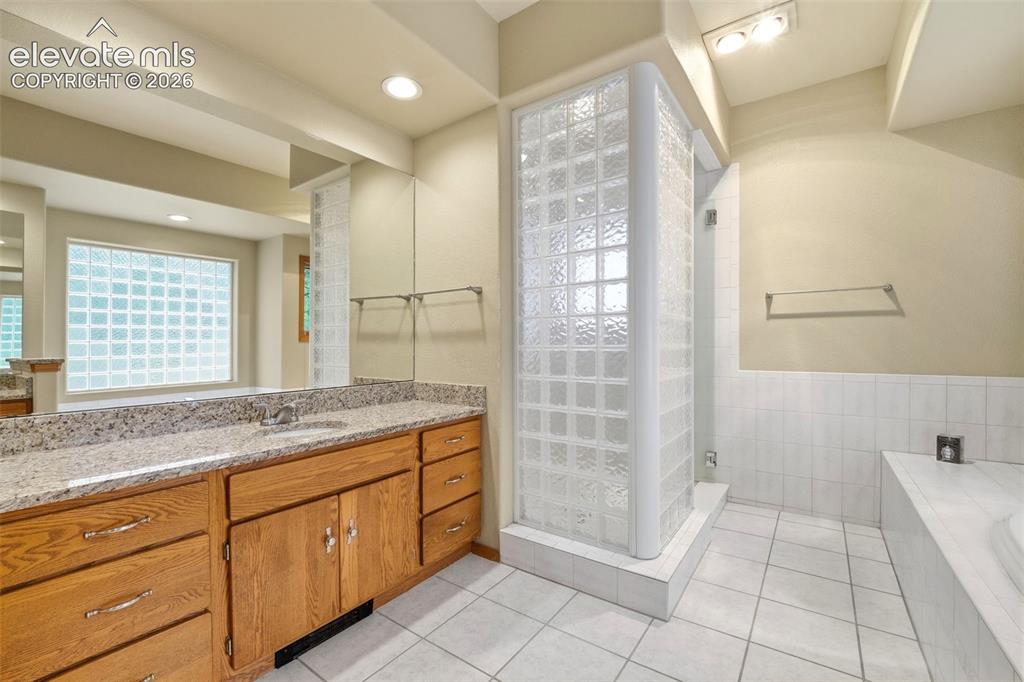 Image 18 of 40: Bathroom featuring a double vanity with wood cabinetry, granite-finish coun