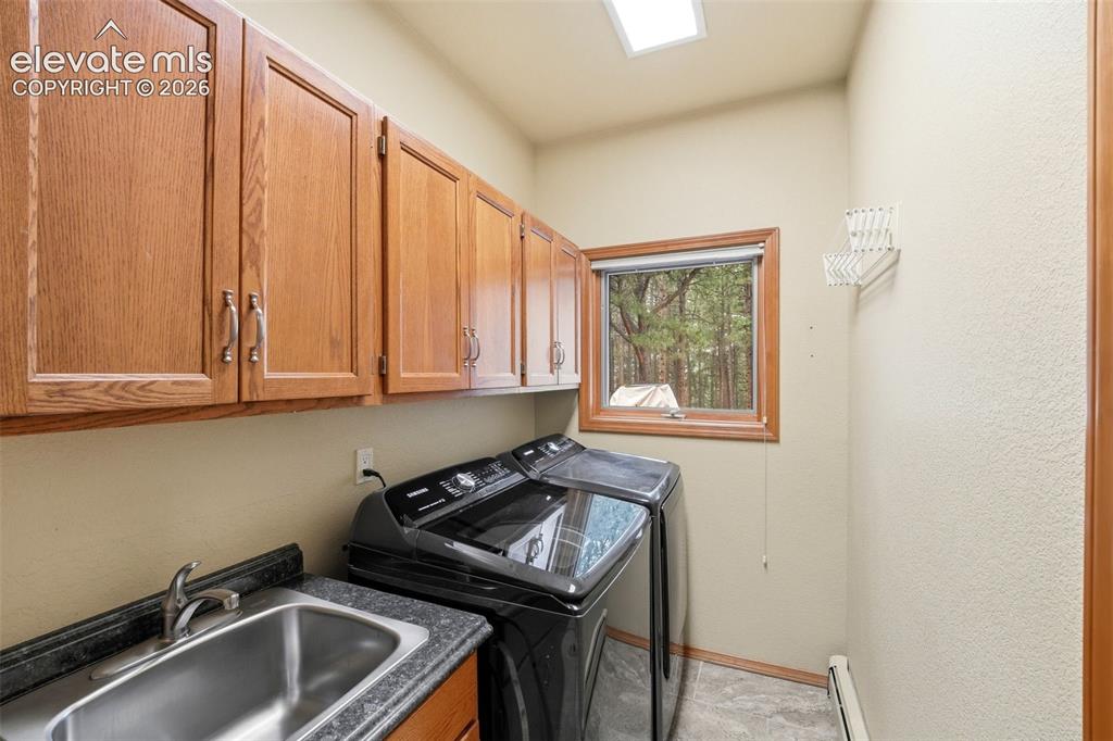 Image 21 of 40: Utility room featuring wood-finish cabinetry with silver-tone hardware, a s