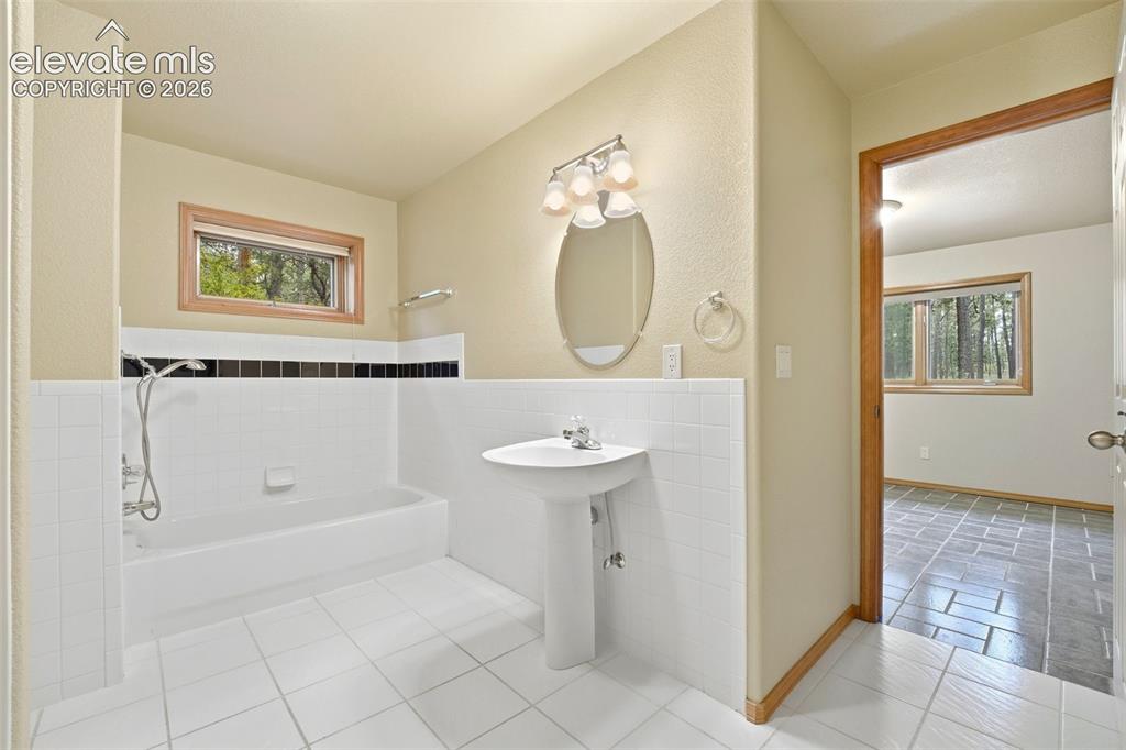 Image 22 of 40: Bathroom featuring a pedestal sink, oval mirror with vanity lighting, and a