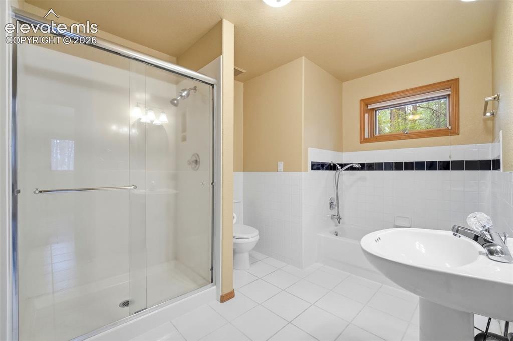 Image 23 of 40: Bathroom featuring a glass-enclosed shower, pedestal sink, and a combinatio