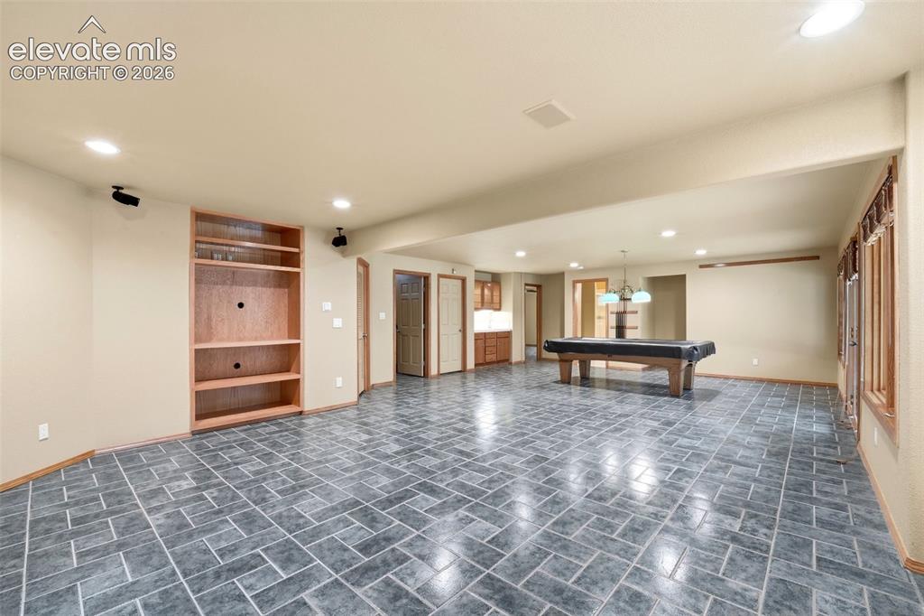 Image 24 of 40: Spacious room featuring gray tile flooring, recessed lighting, and a built-