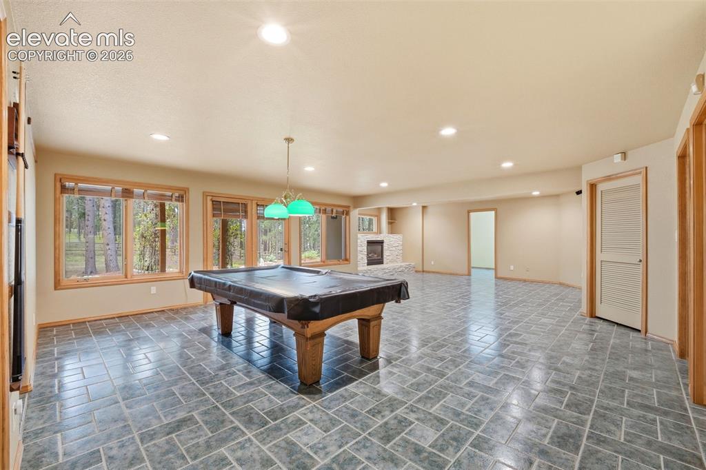 Image 26 of 40: Spacious recreational room featuring gray tile flooring and recessed lighti