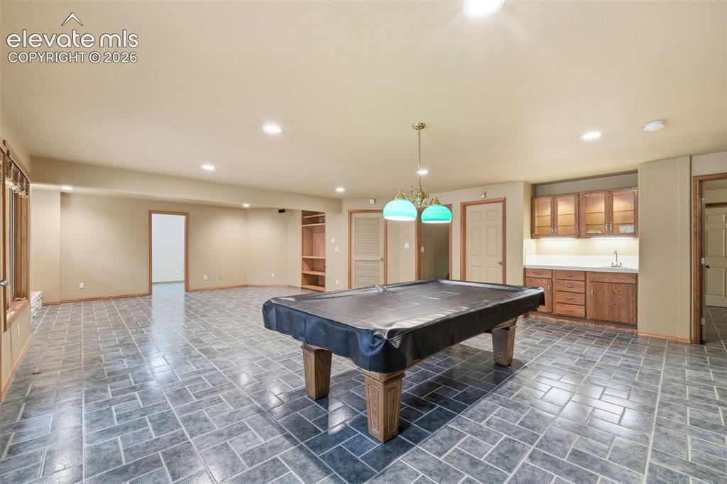 Image 28 of 40: Spacious recreation room featuring robust tile flooring, a built-in wet bar
