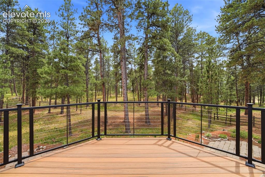 Image 32 of 40: Spacious outdoor deck with wood-finish flooring and black metal cable raili
