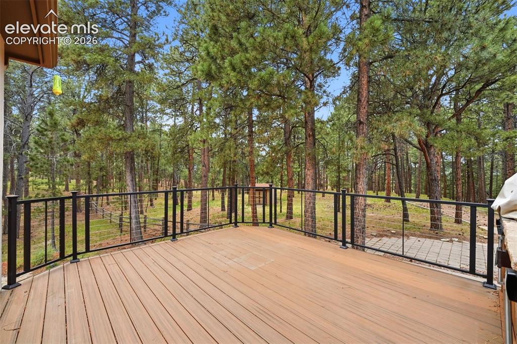Image 33 of 40: Expansive outdoor deck featuring wood-finish flooring and a black metal rai