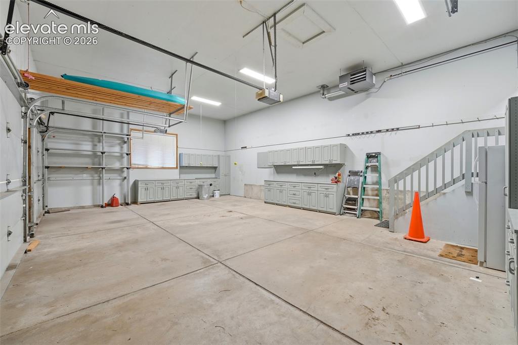 Image 38 of 40: Concrete flooring garage featuring extensive cabinetry, overhead storage, i