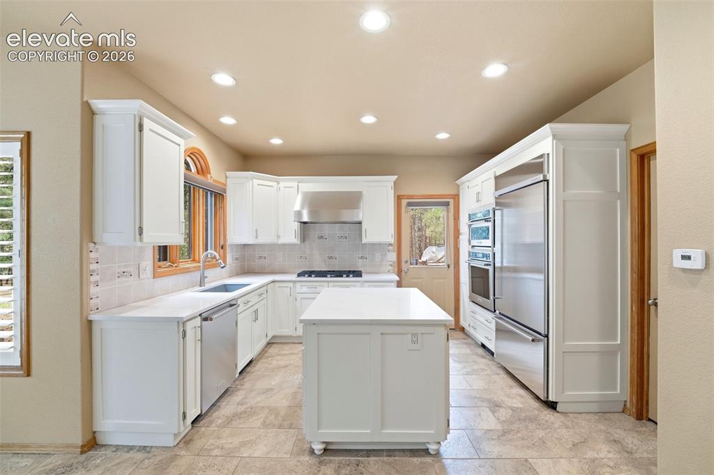 Image 4 of 40: Kitchen featuring white cabinetry, light countertops, stainless steel appli
