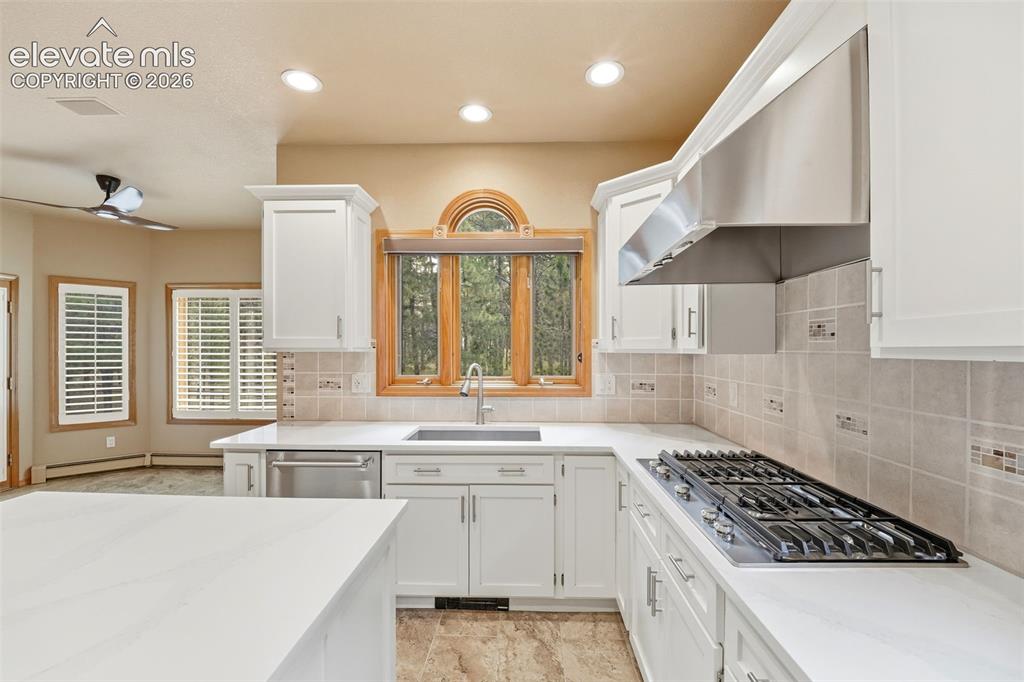 Image 8 of 40: Kitchen featuring white cabinetry, light countertops, stainless steel appli