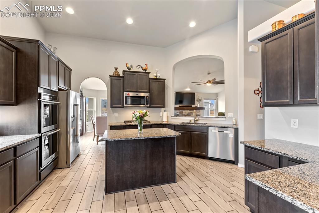 Image 11 of 41: Kitchen featuring ceramic tile flooring, dark wood cabinetry, and granite c
