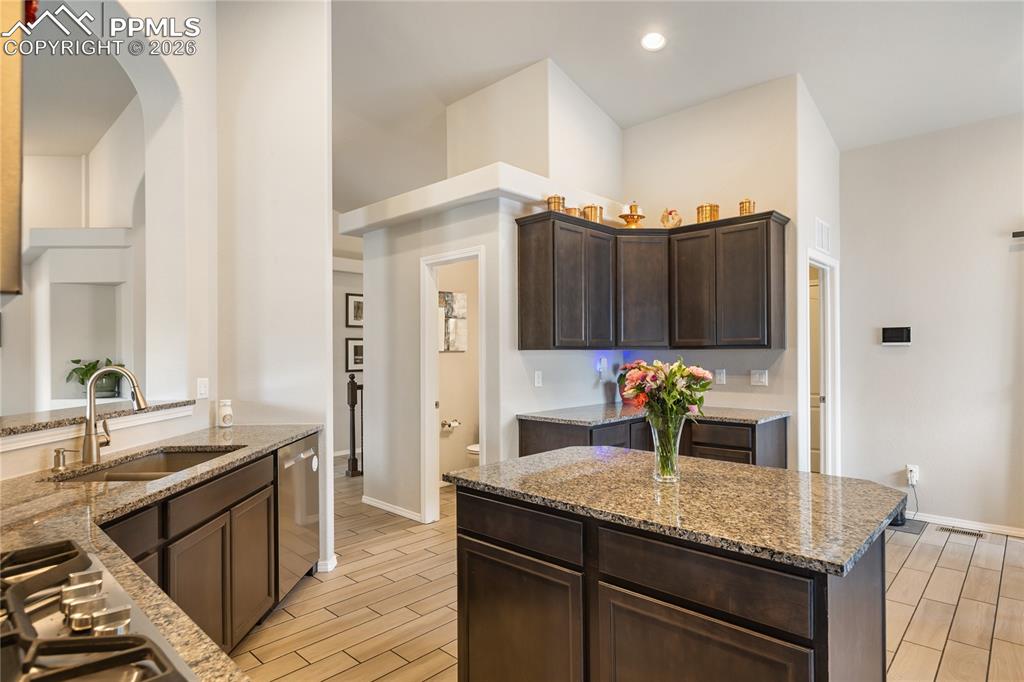 Image 12 of 41: Kitchen featuring a central island, dark wood cabinetry, granite countertop