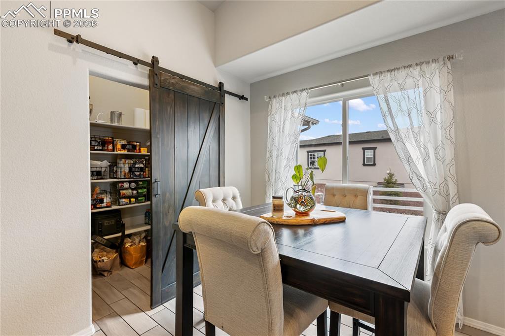 Image 13 of 41: Barn door pantry with extensive shelving, ceramic tile flooring, and natura