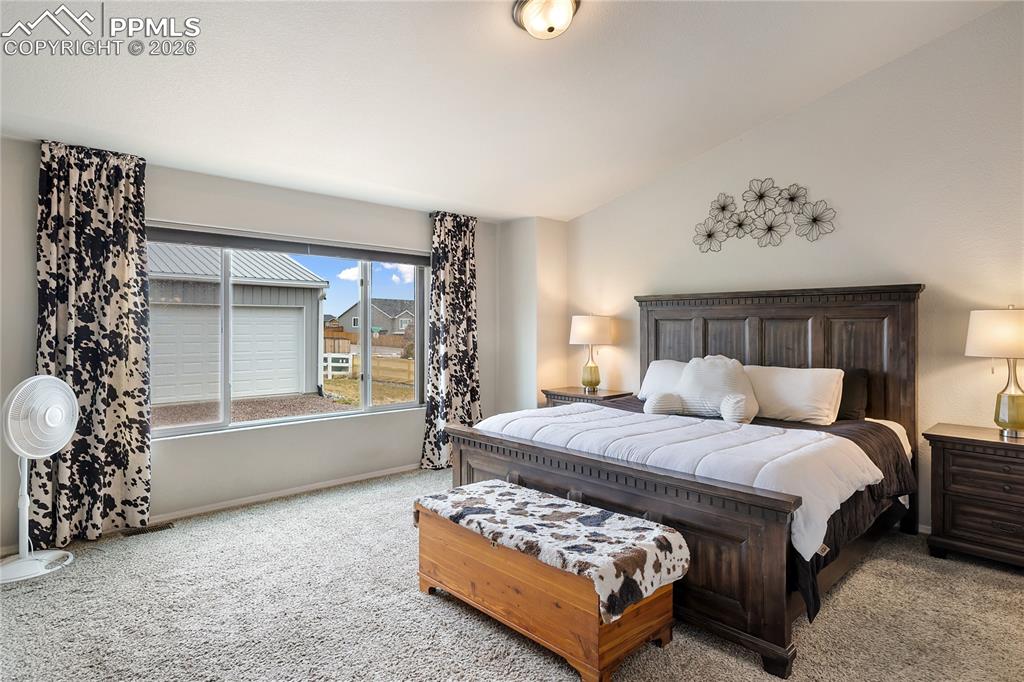 Image 19 of 41: Spacious primary bedroom featuring vaulted ceilings, a large window, and so