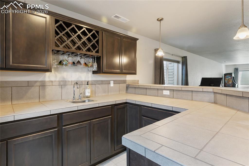 Image 27 of 41: Bar with tile counters and built-in wine storage