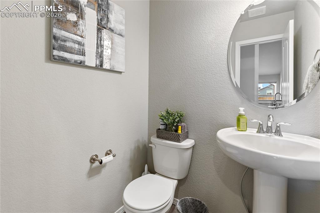 Image 32 of 41: Convenient main-level powder bathroom with pedestal sink and modern finishe