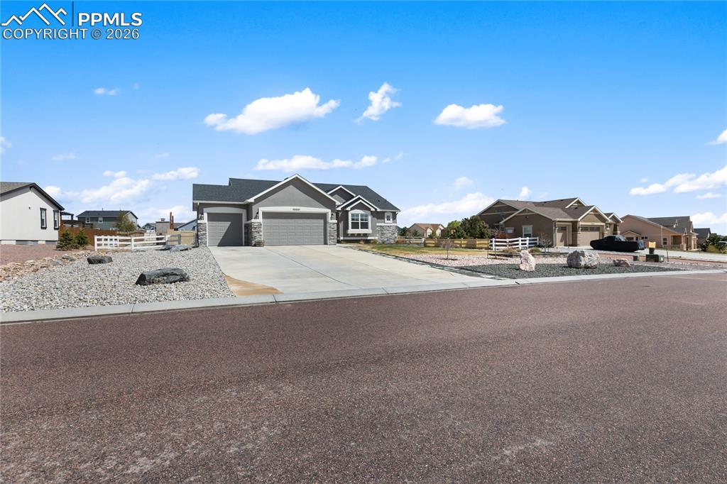 Image 39 of 41: Ranch-style home featuring a gray facade with stone accents, an attached th