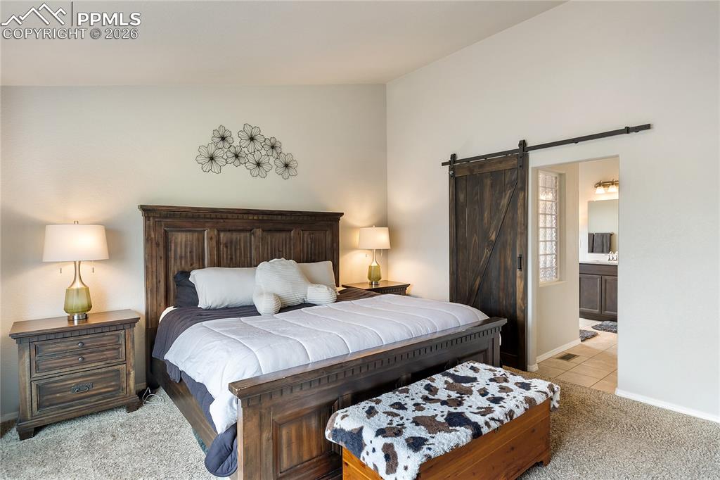 Image 5 of 41: Spacious primary bedroom with light-toned walls, plush carpeting, and a dar