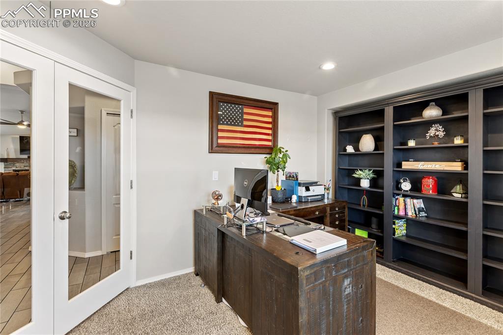 Image 7 of 41: Dedicated office space with French doors, custom built-ins, and room for wo