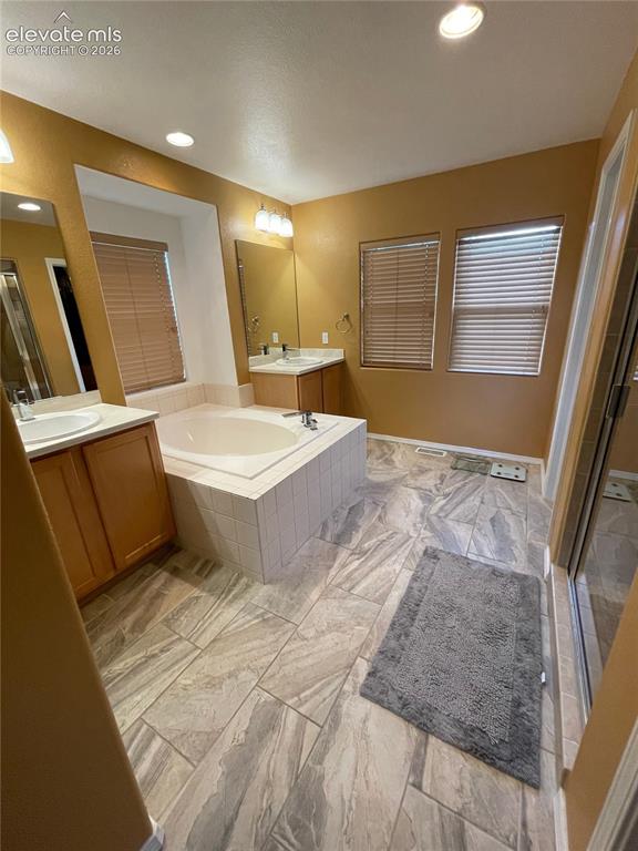 Image 10 of 27: Expansive bathroom featuring dual vanities, an integrated soaking tub, a se