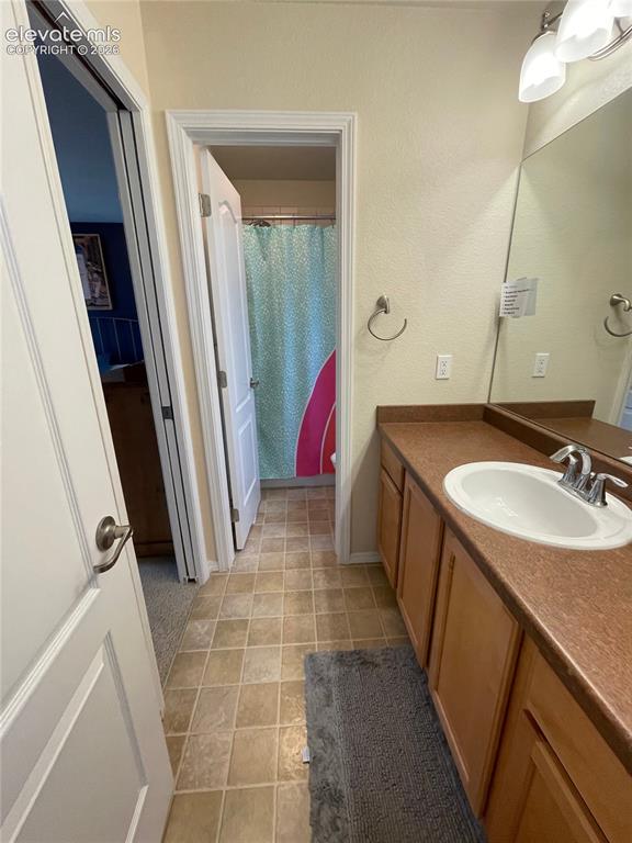 Image 15 of 27: Bathroom vanity with wood-finish cabinetry, a white oval sink, and a brown 