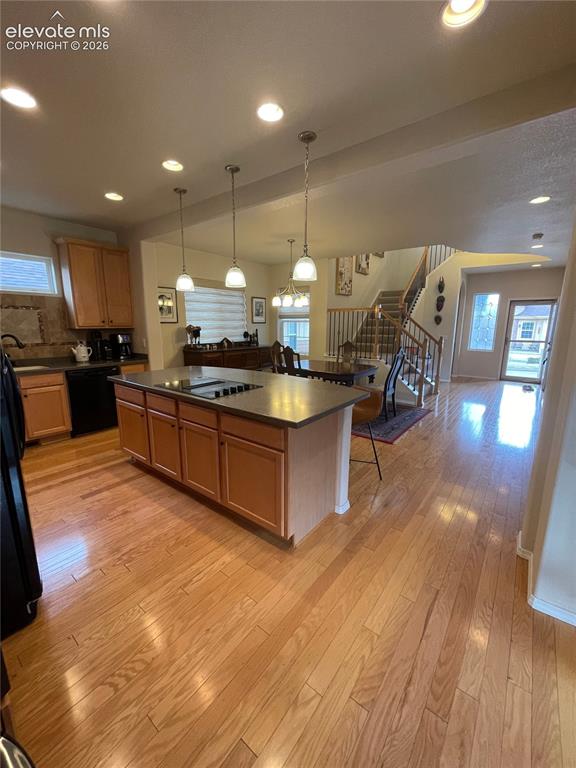Image 5 of 27: Kitchen island with a built-in cooktop, pendant lighting, wood-finish floor
