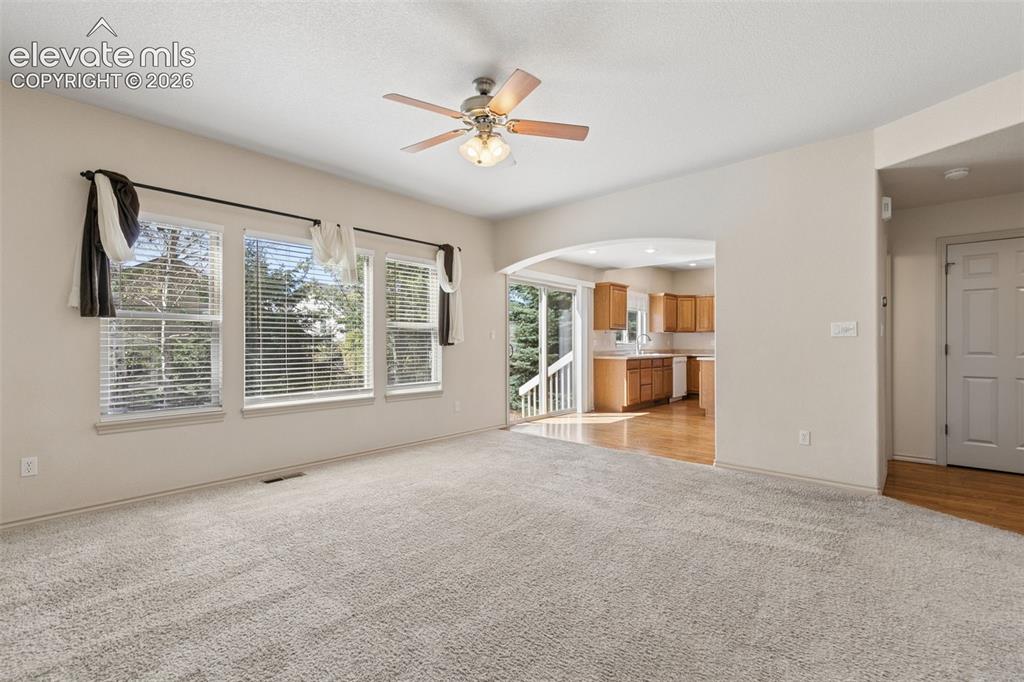 Image 11 of 34: Spacious open-concept living room with a cozy fireplace and access to the b